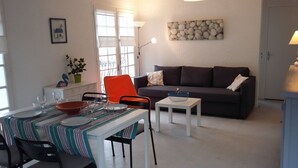 Un espacio habitable compacto con comedor, un sofá, una mesita y una lámpara.