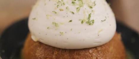 A dessert with a creamy topping on a round base, served on a dark plate.