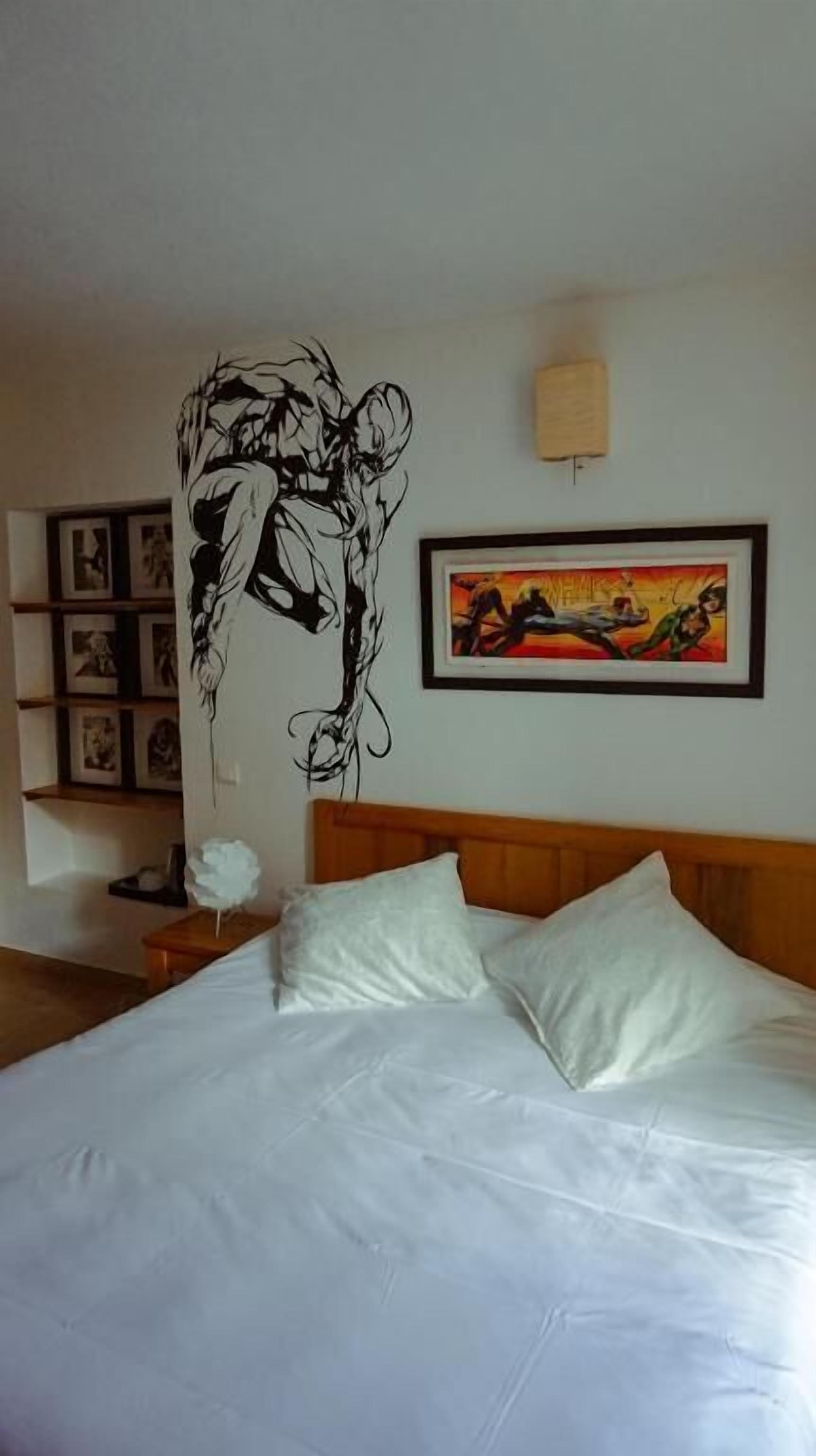 Habitación de hotel con una cama, una obra de arte en la pared, un cuadro enmarcado y una mesita de noche.