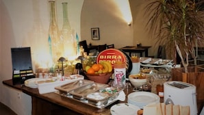 Un buffet de petit-déjeuner avec divers plats, un saladier de fruits et une pancarte indiquant « BIRRA DE’RO ».