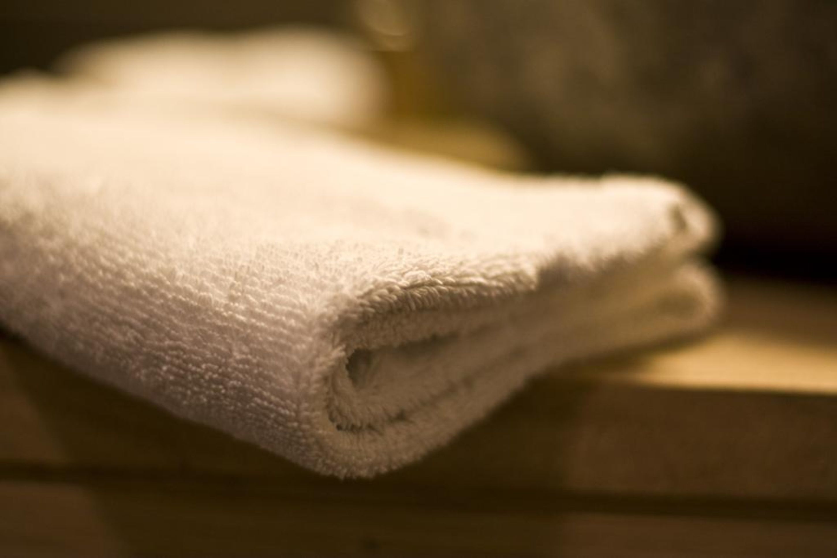 A folded white towel on a wooden surface.