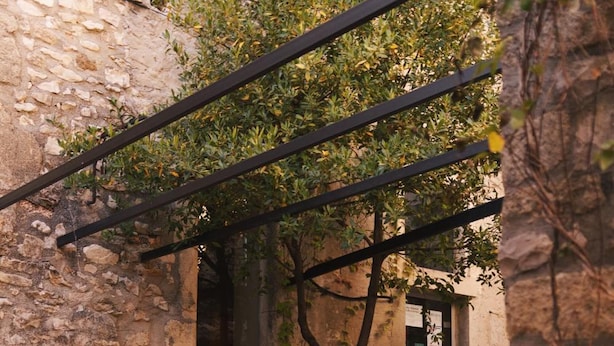 Un espace extérieur aménagé pour les repas, avec des murs en pierre, des chaises et des tables en métal, le tout prêt pour un repas.