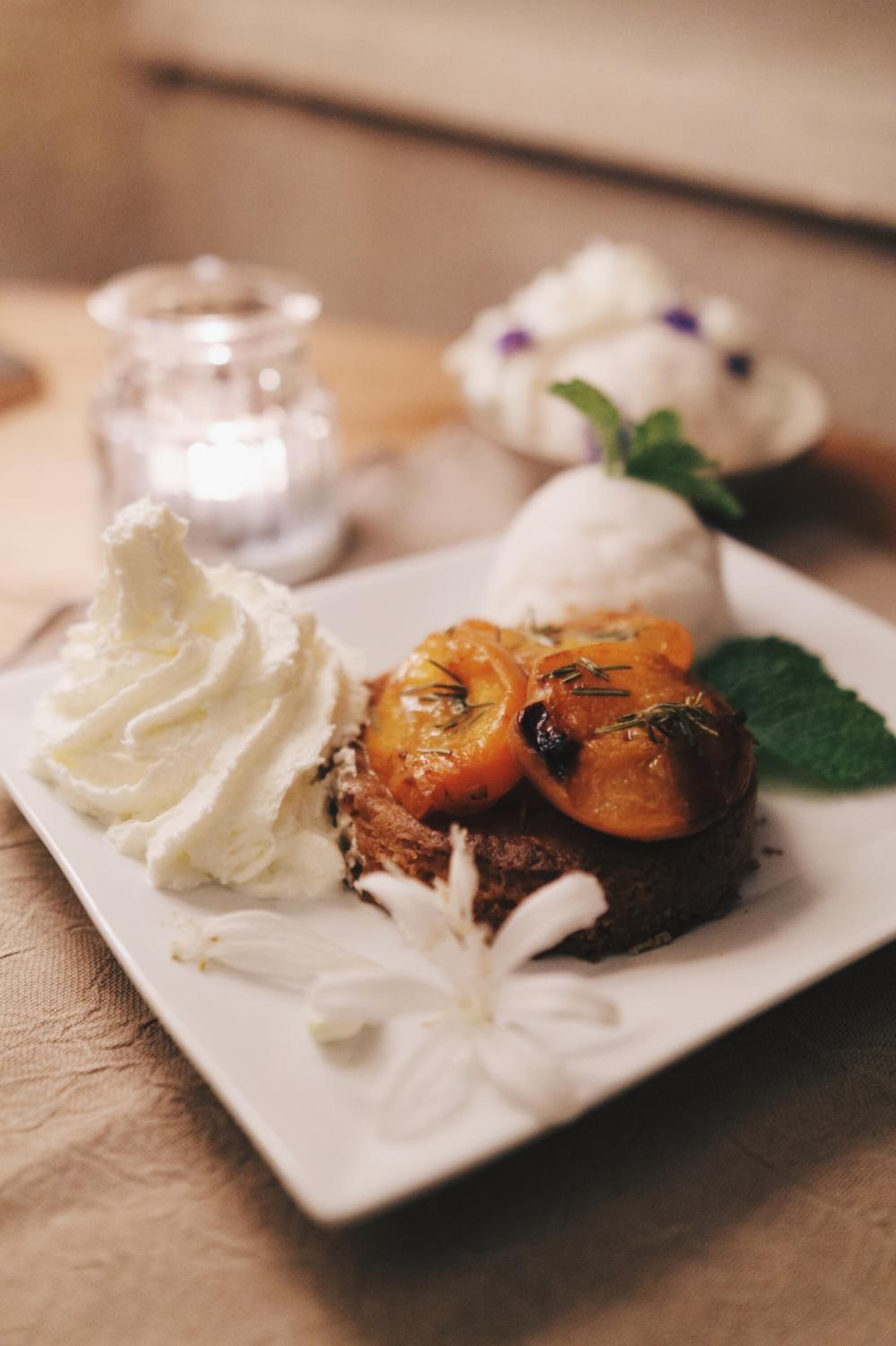 Un plato de postre con un pastel, fruta asada y crema batida.