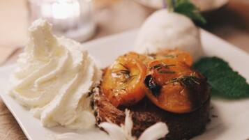 Un plato de postre con un pastel, fruta asada y crema batida.
