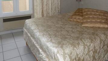 A bedroom with a bed, a window with curtains, and a lamp.
