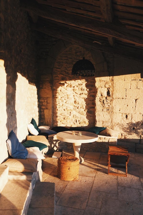 Una habitación con paredes de piedra, una mesa redonda y un taburete de madera.