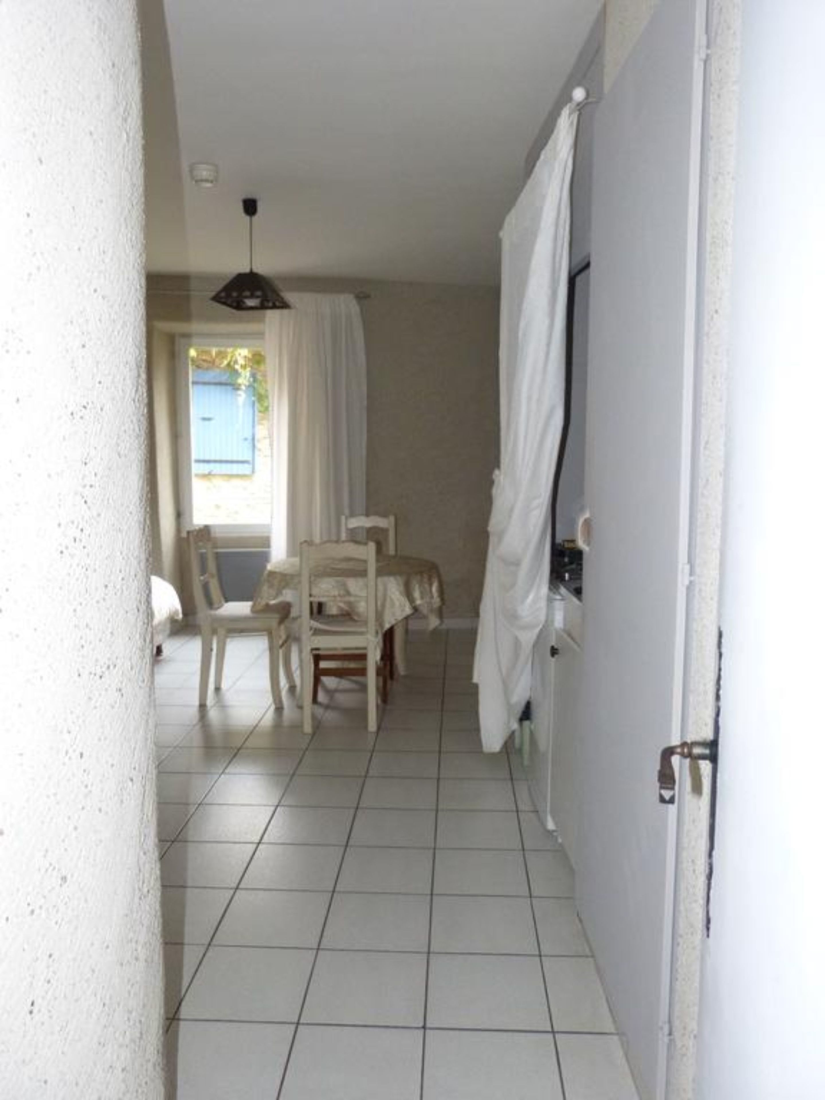 A room with a tiled floor, a white door, a chair, and a table.