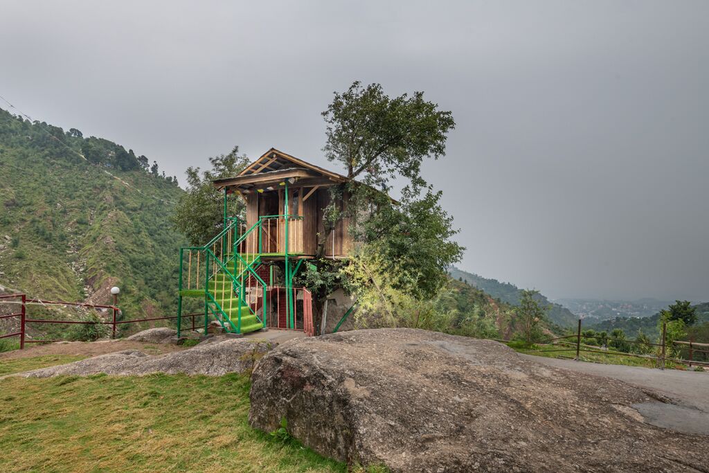 A wooden structure with a staircase, set against a mountainous backdrop.