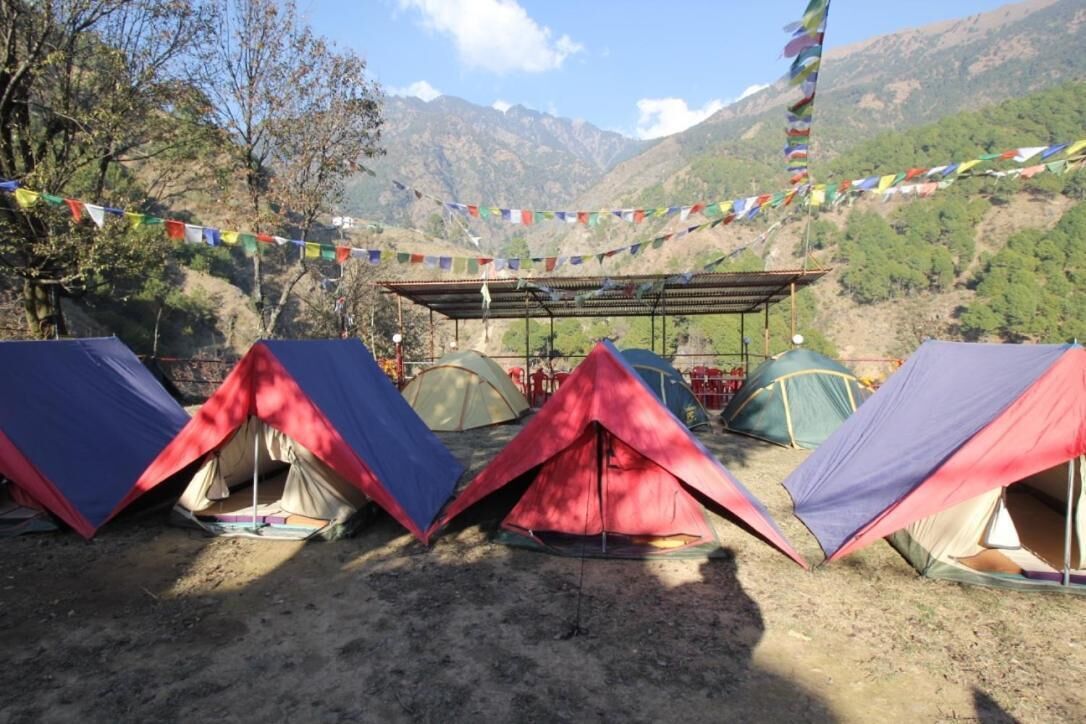 Una hilera de tiendas de campaña en un área de camping con montañas al fondo.
