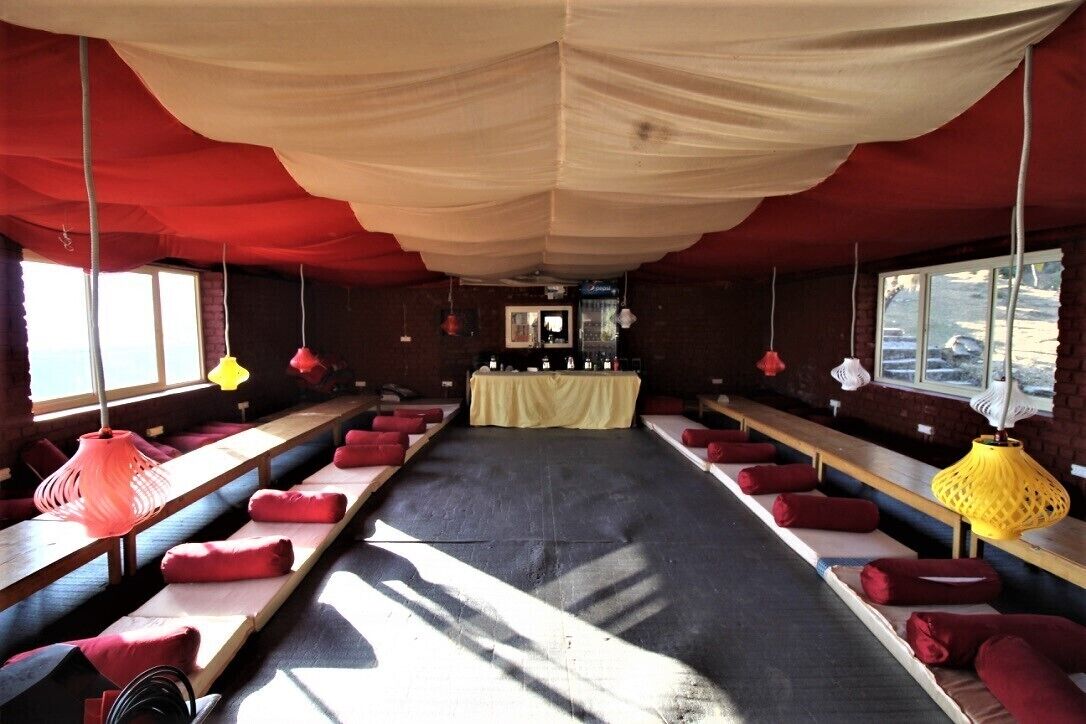 A room with long benches, red cushions, and hanging lamps.