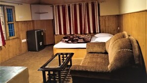 Une pièce de taille modeste comprenant un lit, un canapé, une petite table et un réfrigérateur.
