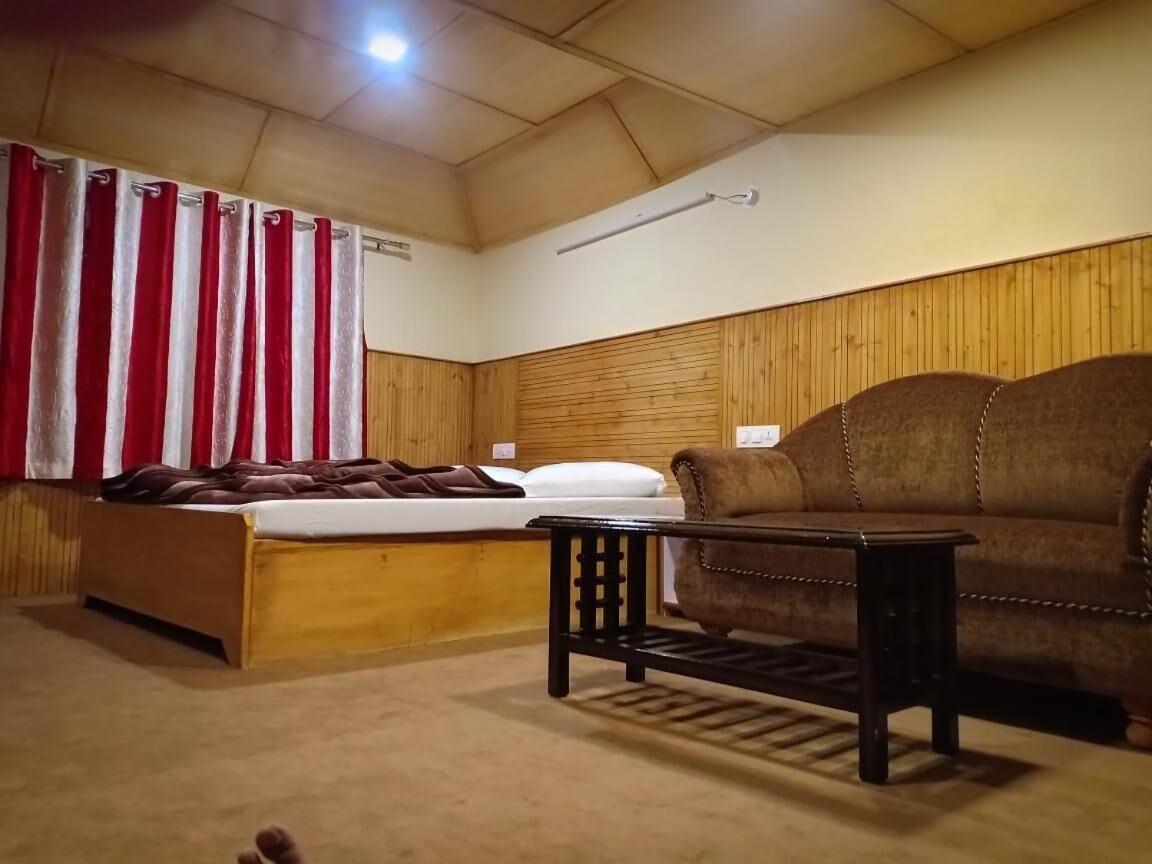 A room with a wooden bunk bed, a brown sofa, and a small table.
