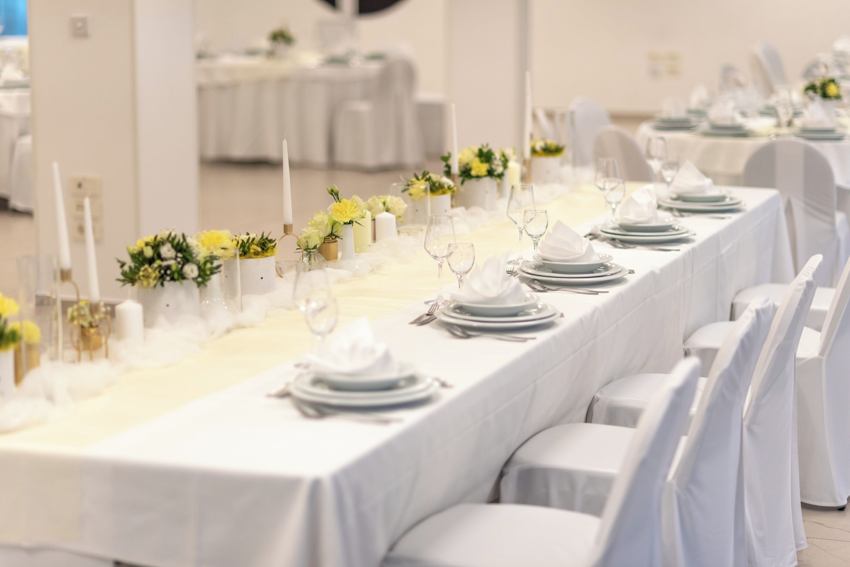 A long banquet table set with white tablecloths, candles, and floral centerpieces.