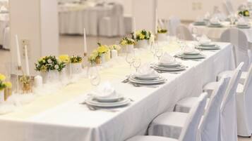 A long banquet table set with white tablecloths, candles, and floral centerpieces.