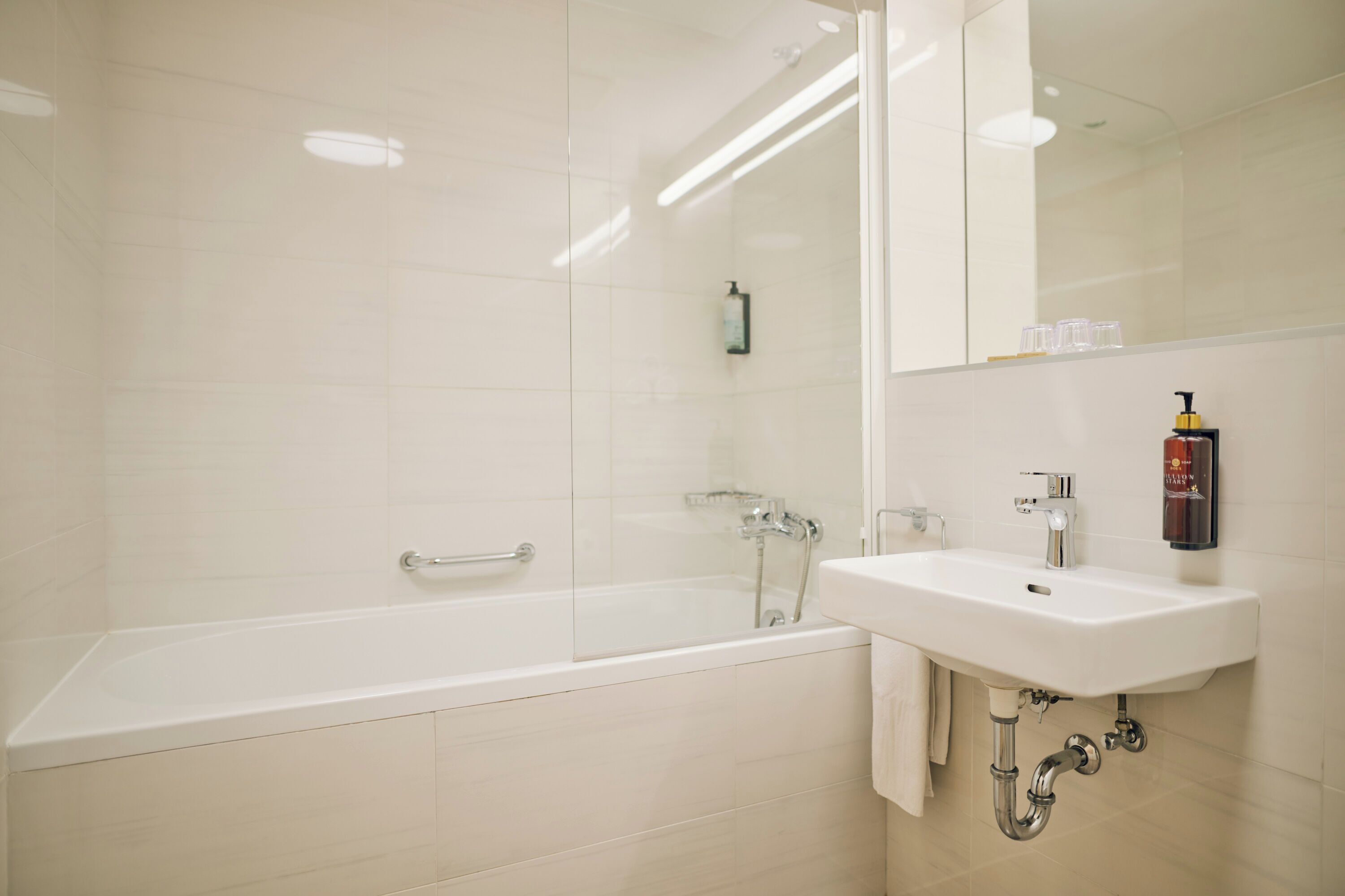 A modern bathroom with a bathtub, a sink, and a mirror.