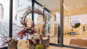 Een hotelingang met een decoratieve presentatie, waaronder een krans, decoraties in de vorm van een huis en potplanten.