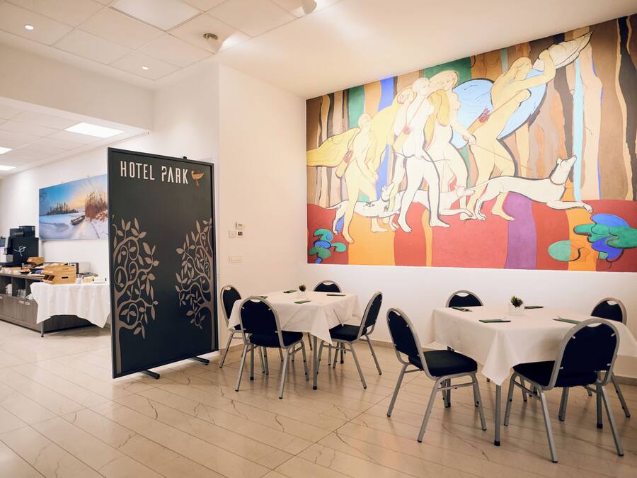 Ein Hotelrestaurant mit gedeckten Tischen für Gäste, einem großen Wandbild und einem 'HOTEL PARK' Schild.