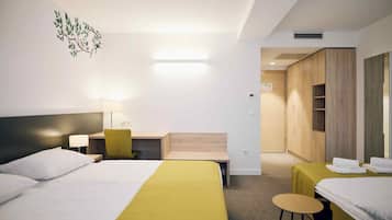 Habitación de hotel con dos camas, un escritorio, una silla y un armario.