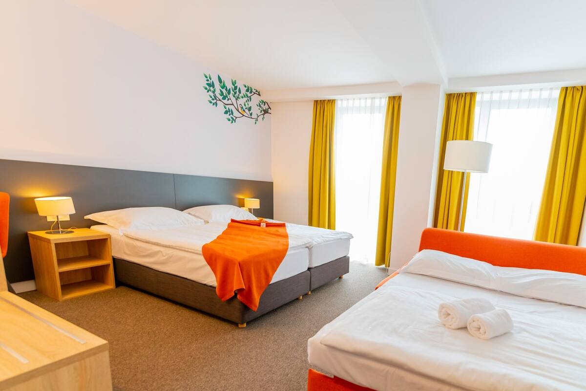 Une chambre d’hôtel avec deux lits, une table de chevet, une lampe et un élément décoratif mural.