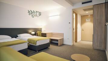 A hotel room with two beds, a desk, a chair, and a small table.