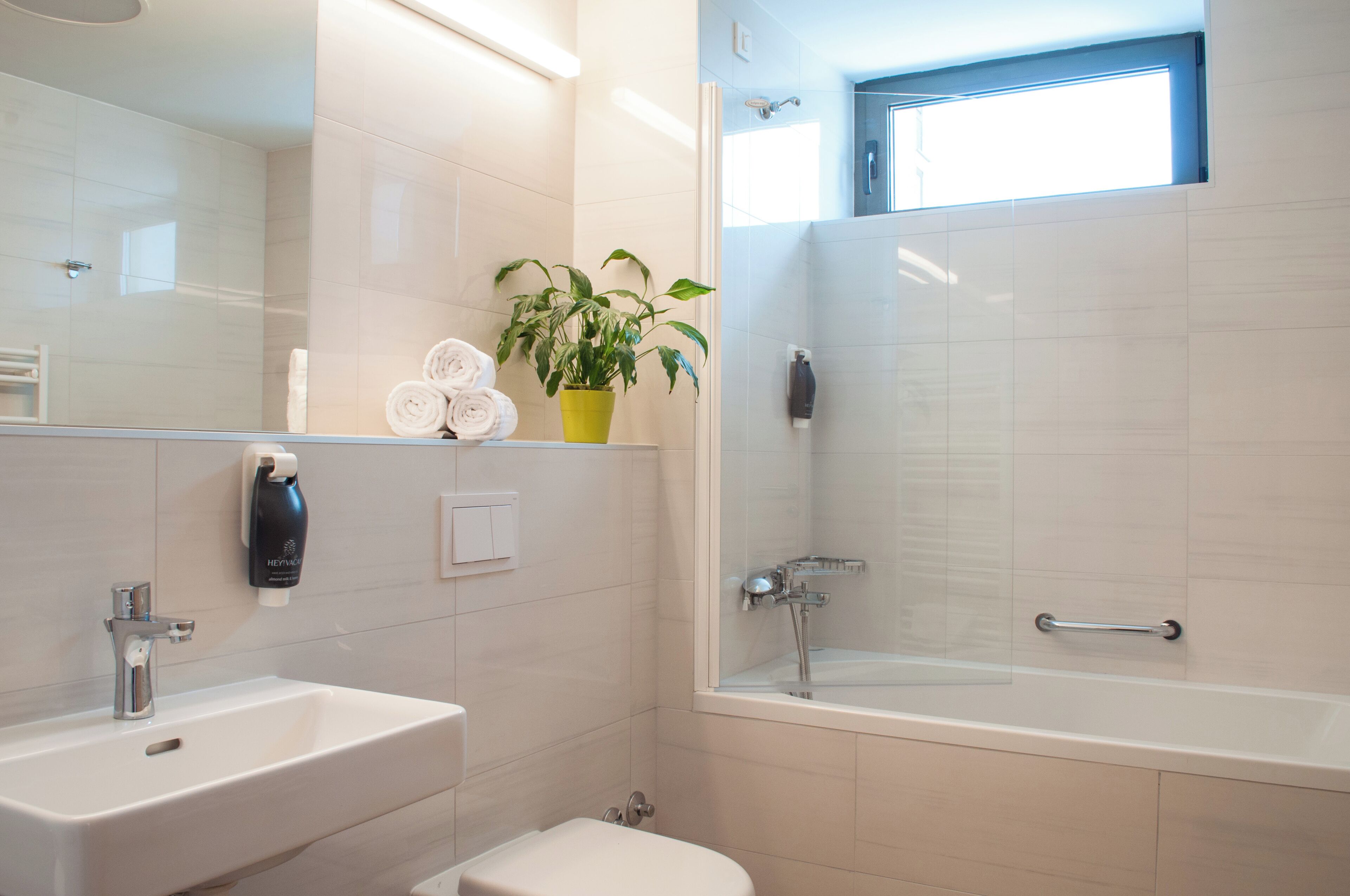 Un baño moderno con lavamanos, inodoro y cabina de ducha con mampara de vidrio.