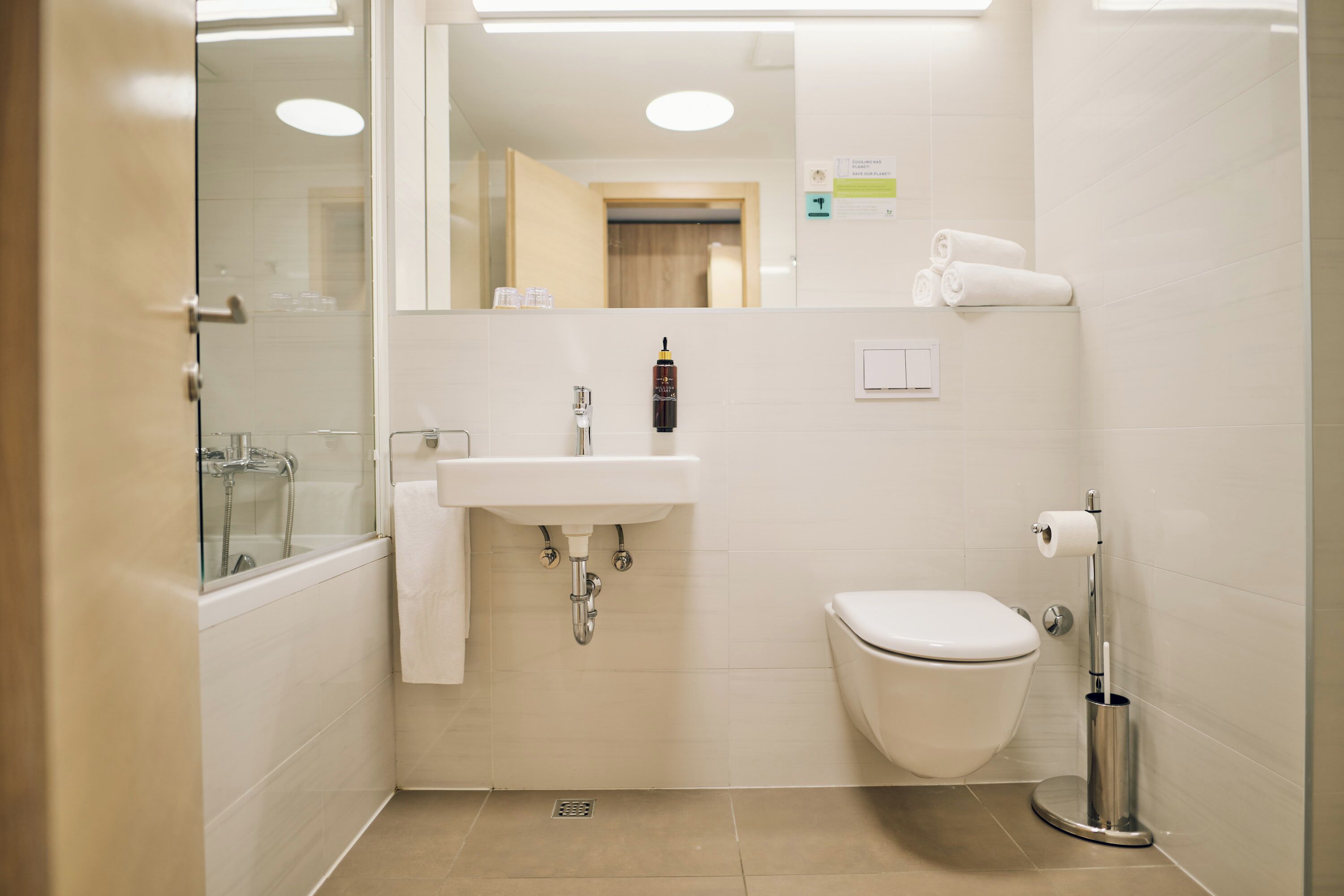 A modern bathroom with a glass shower enclosure, a sink, a toilet, and a towel rack.