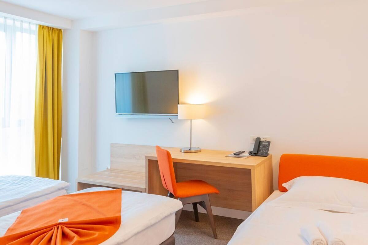 Une chambre d’hôtel avec deux lits, un bureau, une chaise, une télévision et un téléphone.