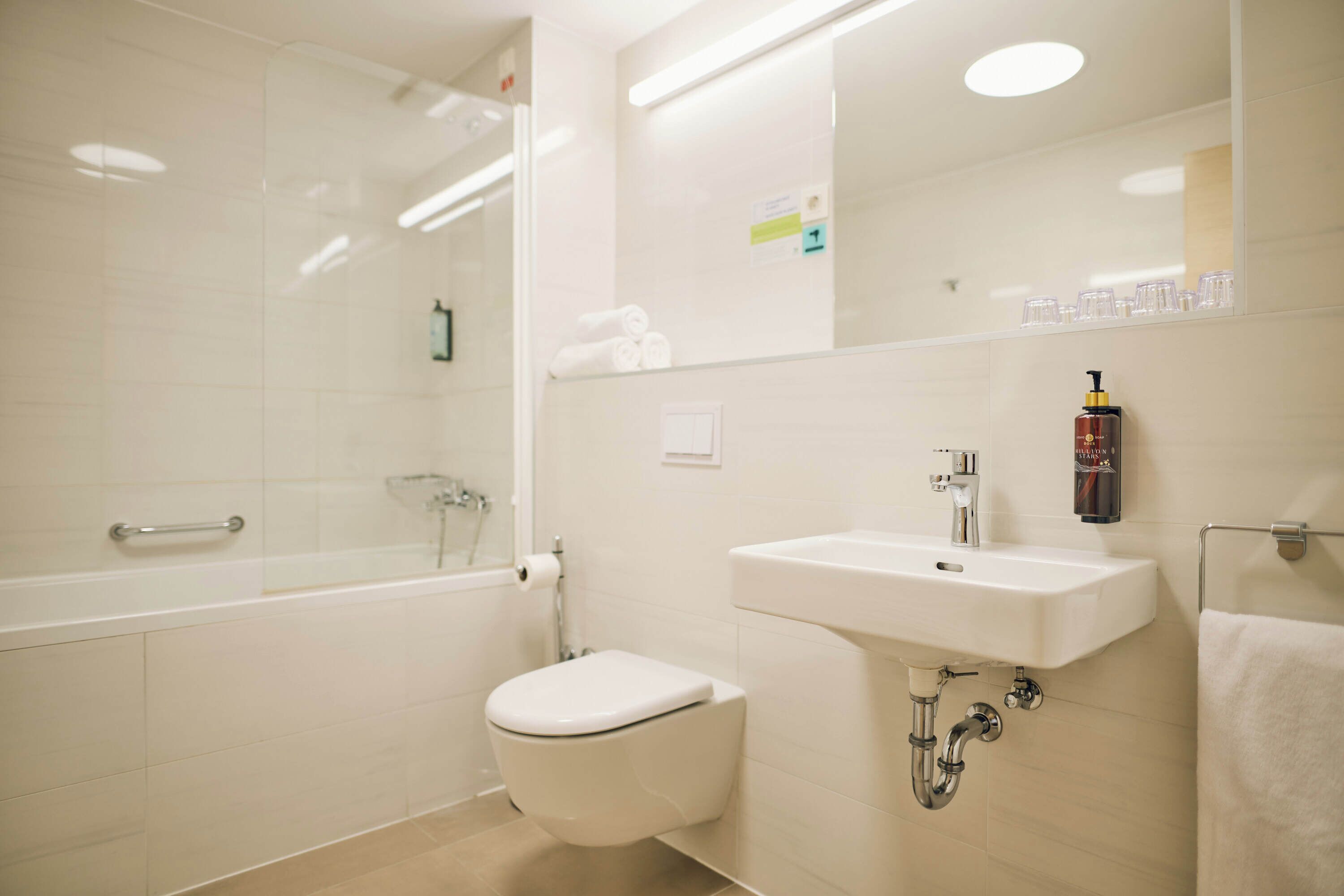 Et moderne badeværelse med badekar, toilet, vask og en brusekabine i glas.