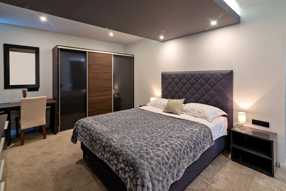 Une chambre moderne avec un grand lit, un bureau et une armoire.