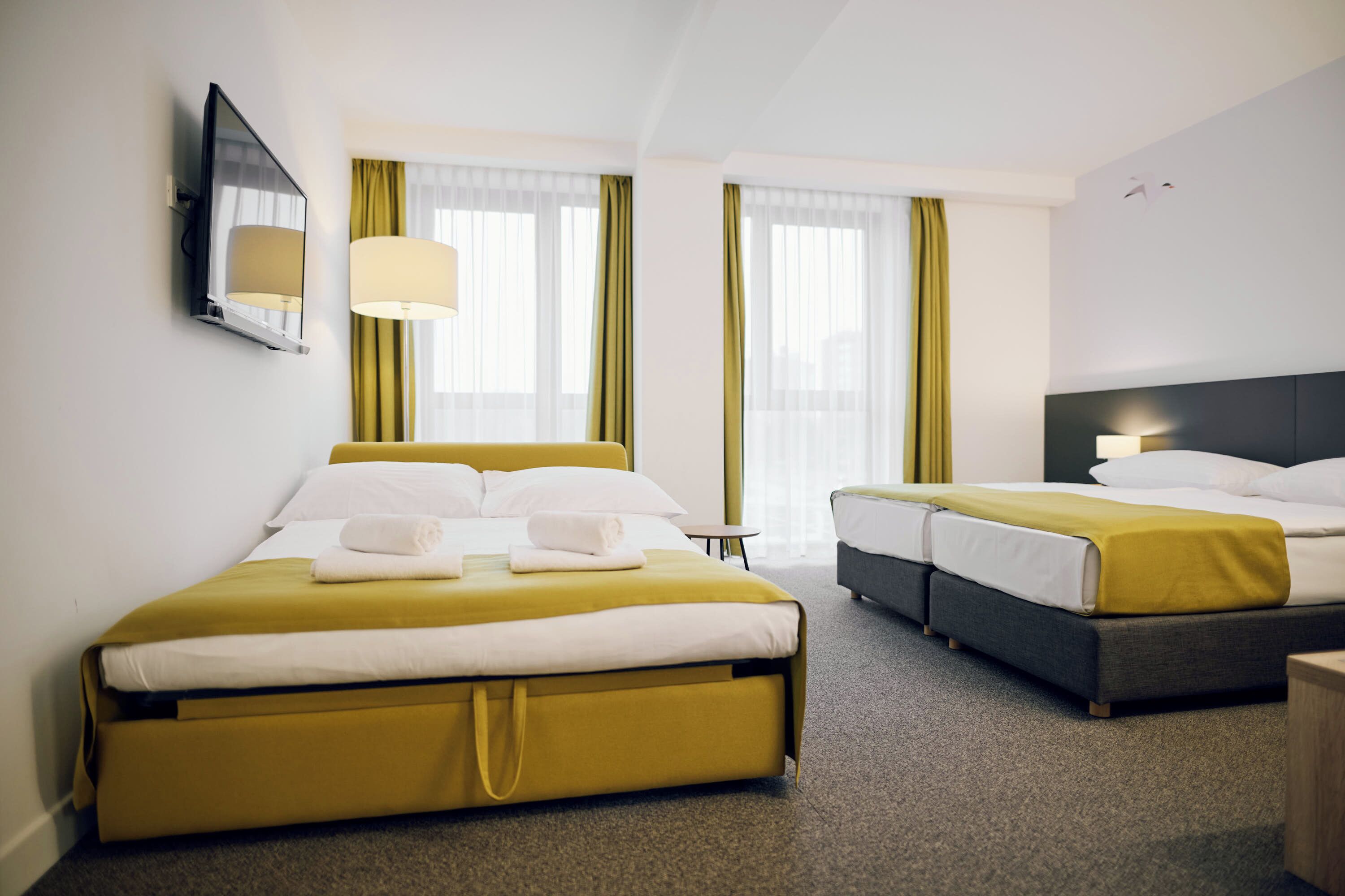 Habitación de hotel con dos camas, un espejo grande y una ventana con cortinas.