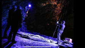 Two people in a dimly lit cave with a flashlight and a shovel. - Self Catering Holidays in the uk (Blaenau Ffestiniog)