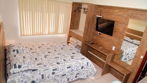 A bedroom with a bed, a TV, a mirror, and a window with blinds. - Residencial Mandino - Quality, conformity and safety (Jardim Iguaçú)