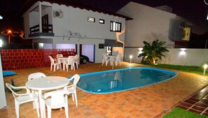 Une maison à deux étages avec une piscine, du mobilier de jardin et une clôture rouge.