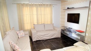 A living room with a sofa, a TV mounted on the wall, and a small entertainment unit. - Residencial Mandino - Quality, conformity and safety (Jardim Iguaçú)