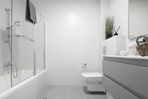 A modern bathroom with a glass-enclosed shower, a white toilet, and a vanity with a mirror.