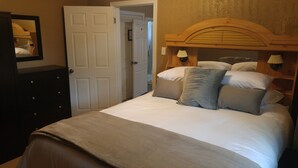 Un dormitorio con cama, cómoda, espejo y puerta.