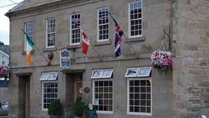 Un edificio de piedra con varias banderas, incluyendo la bandera irlandesa, y un letrero con el número 130.