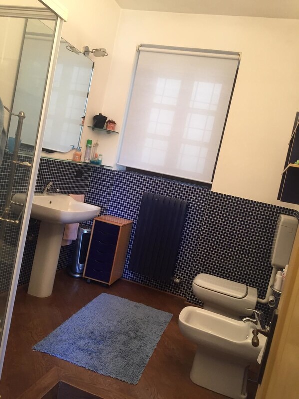 A bathroom with a sink, toilet, and bidet. There is a mirror, a towel rack, and a window with blinds. - Spineto House (Spineto Scrivia)