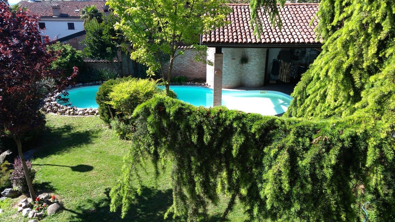 Una piscina rodeada de setos cuidados y un muro de piedra.