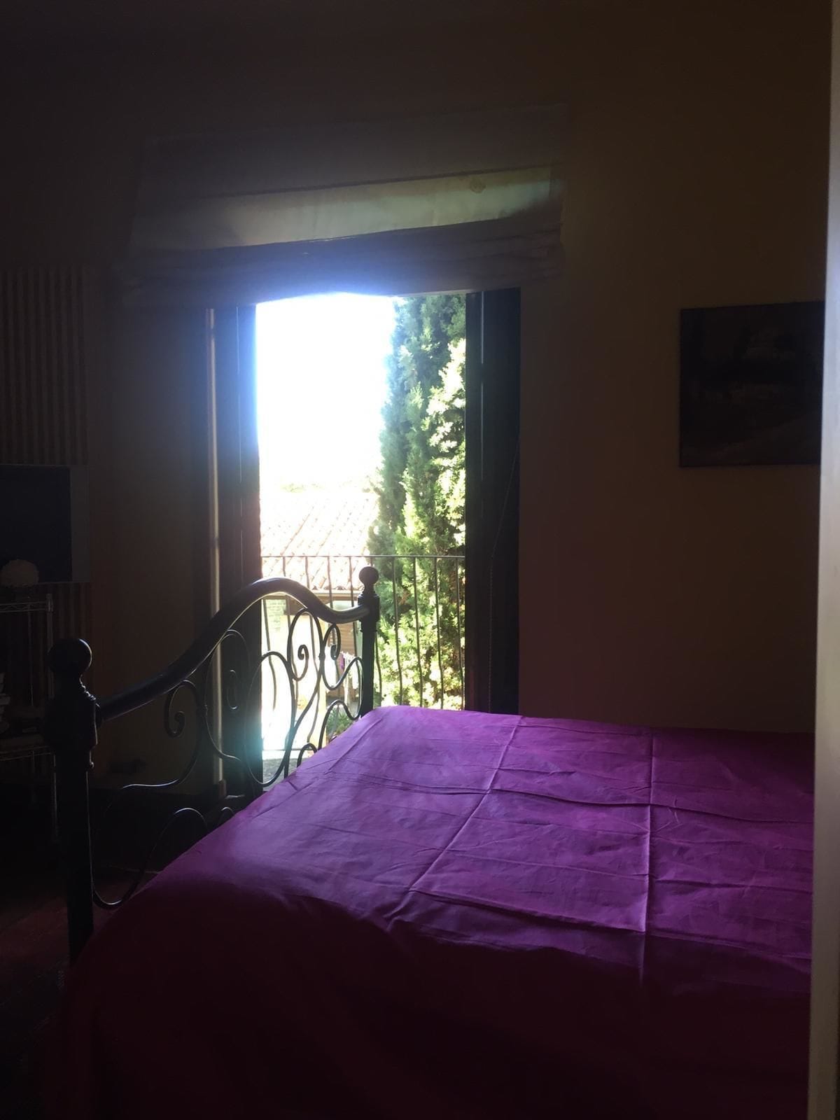 Una habitación con una cama, una ventana y una puerta que da a un espacio exterior.