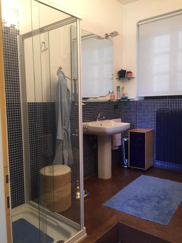 A bathroom with a glass-enclosed shower, a sink, a mirror, and a small cabinet. - Spineto House (Spineto Scrivia)