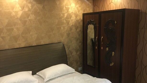Hotellihuone, jossa on sänky, vaatekaappi ja geometrisesti kuvioitu seinä.