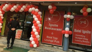 Ignite-ravintolan ulkopuoli: punavalkoinen kyltti, mies seisomassa sisäänkäynnin luona ja ilmapallokaari.
