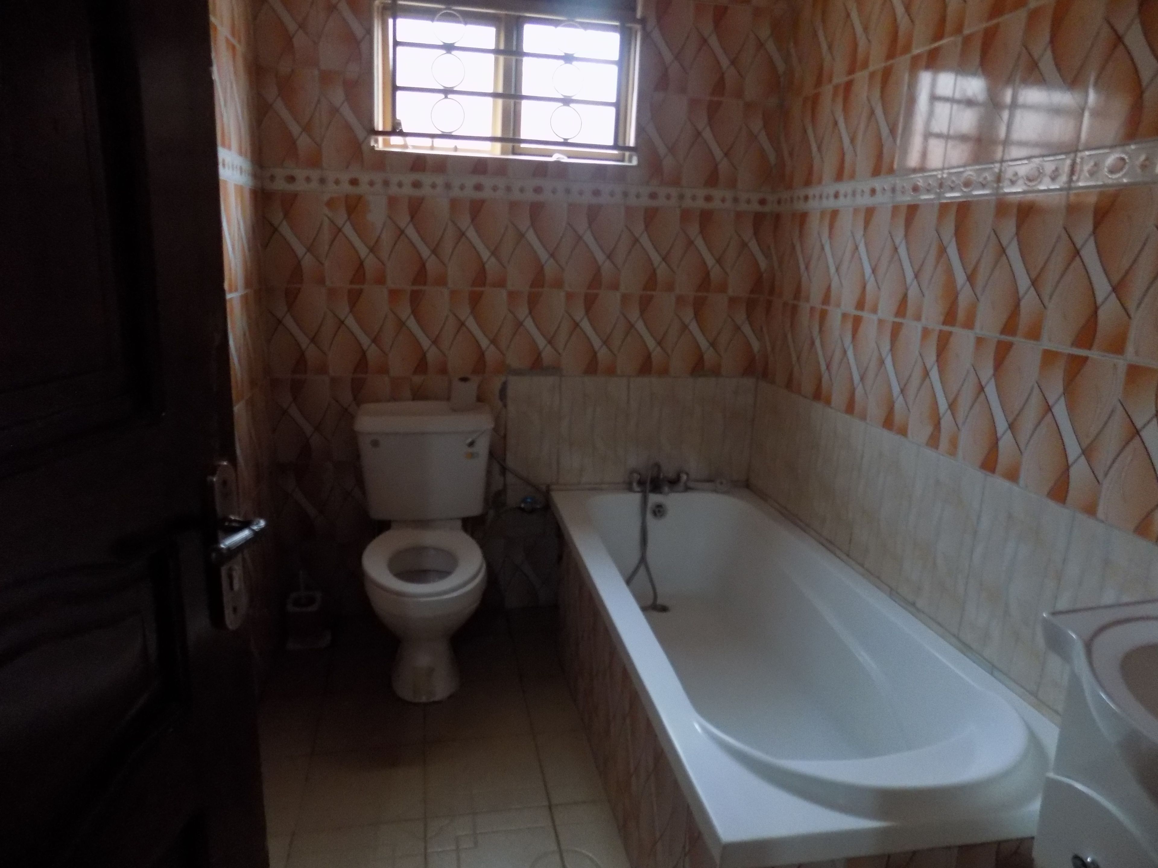 Een badkamer met toilet, bad en een raam.