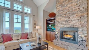 Una sala de estar con chimenea de piedra, un sofá con cojines, una mesa de centro y una estantería.