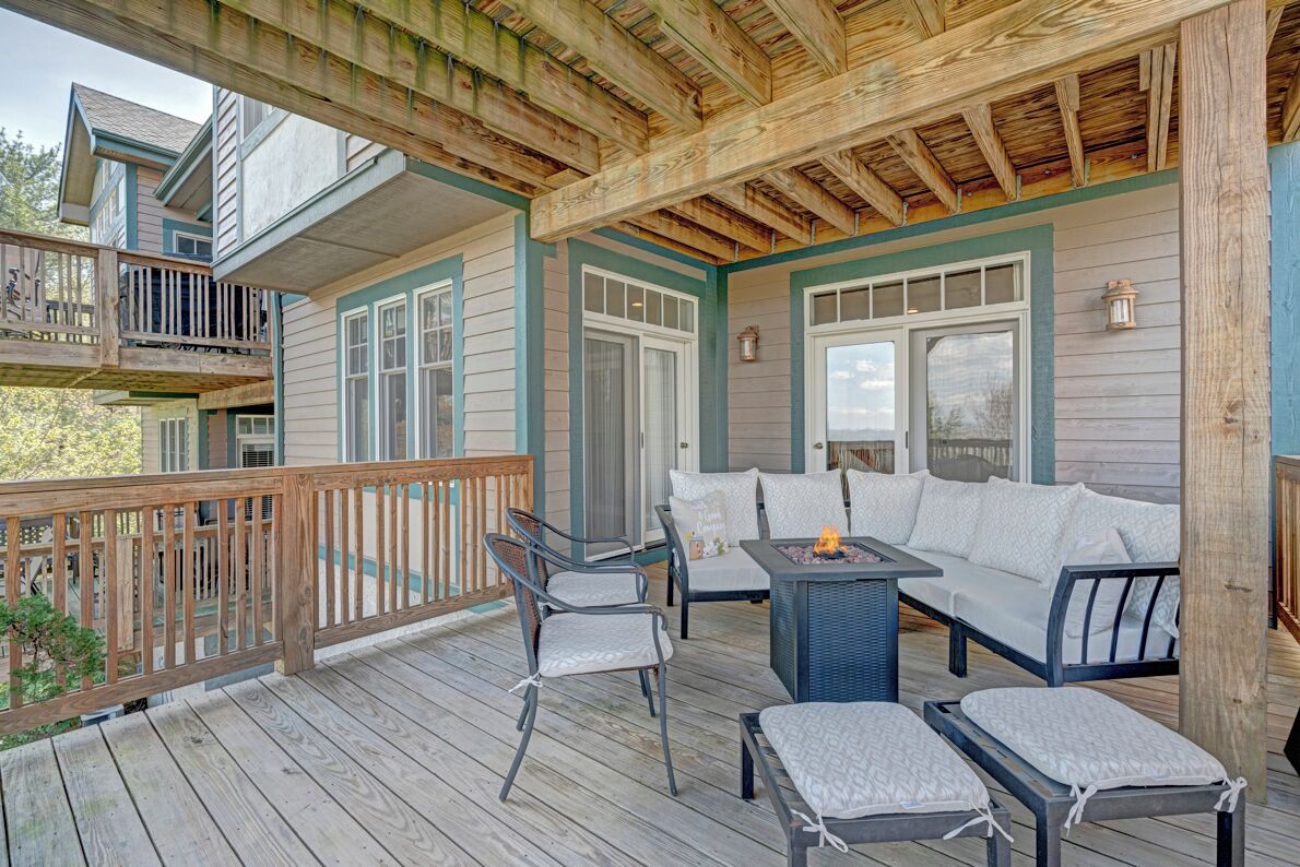 Une terrasse extérieure couverte, aménagée avec un canapé, des fauteuils et un foyer.