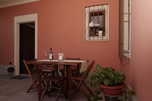 A dining area with a wooden table and chairs, a potted plant, and a window with a metal frame.