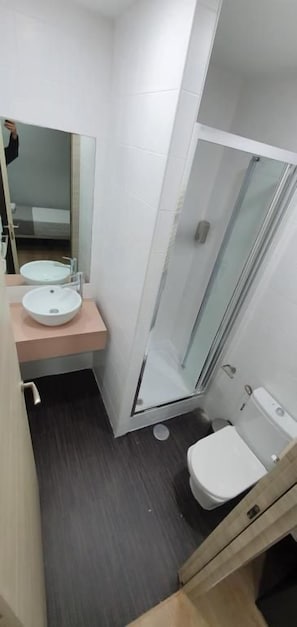 A bathroom with a glass-enclosed shower, a sink, and a toilet.