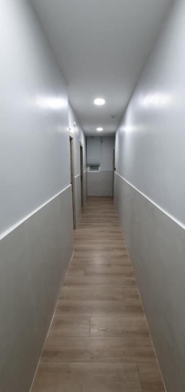 A narrow, well-lit hallway with wooden flooring and white walls. - CH Lemon Rooms By HEBEROOMS (Madrid)