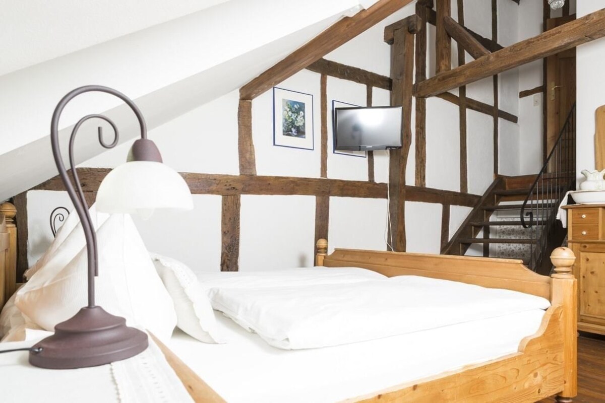 Une chambre à coucher avec un lit en bois, un bureau avec une lampe, une télévision et un escalier.
